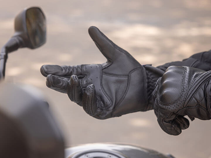 A motorcycle rider putting on protective black gloves