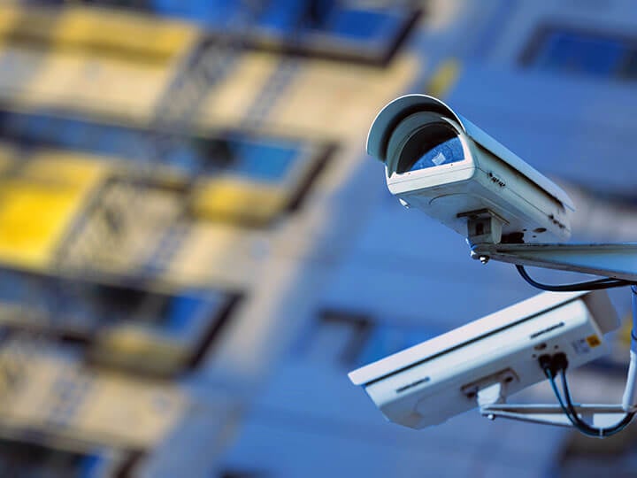 Close up view of two security cameras on the side of a city building