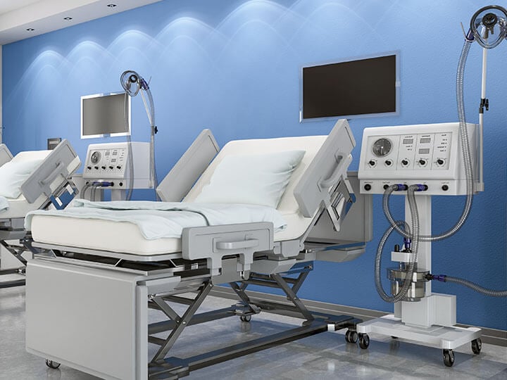 Hospital room with two medical beds and ventilator systems, against a blue wall